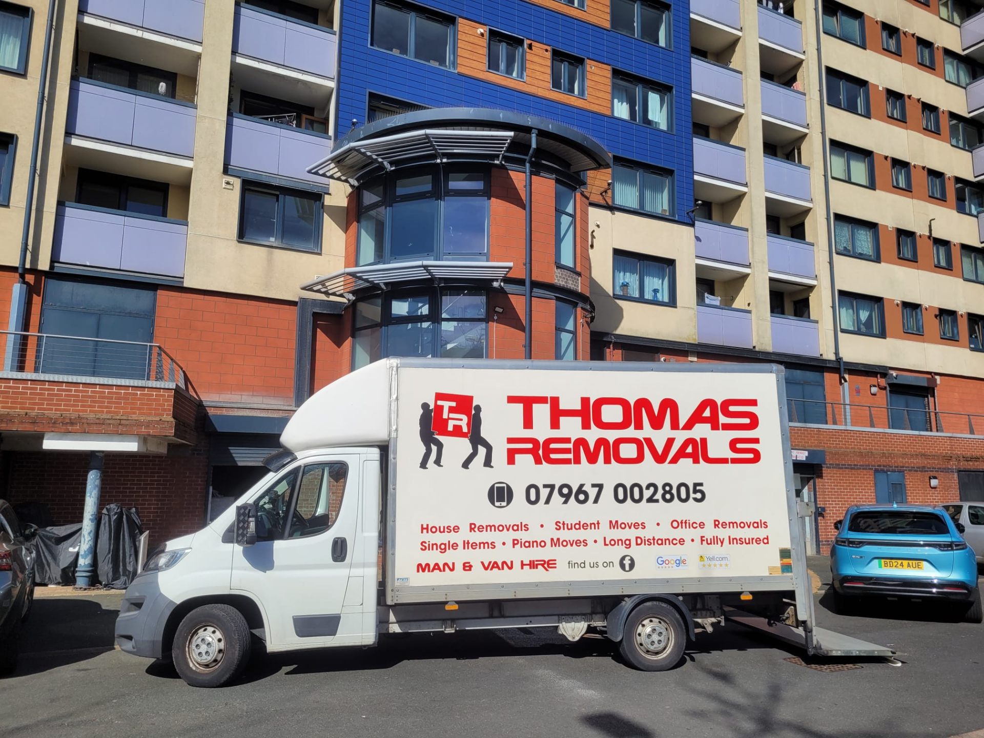 Thomas Removals van at a modern apartment building for a student move